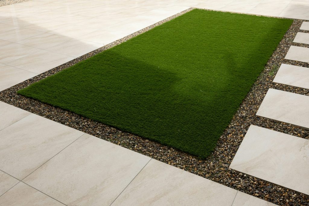 a green grass area in the middle of a walkway